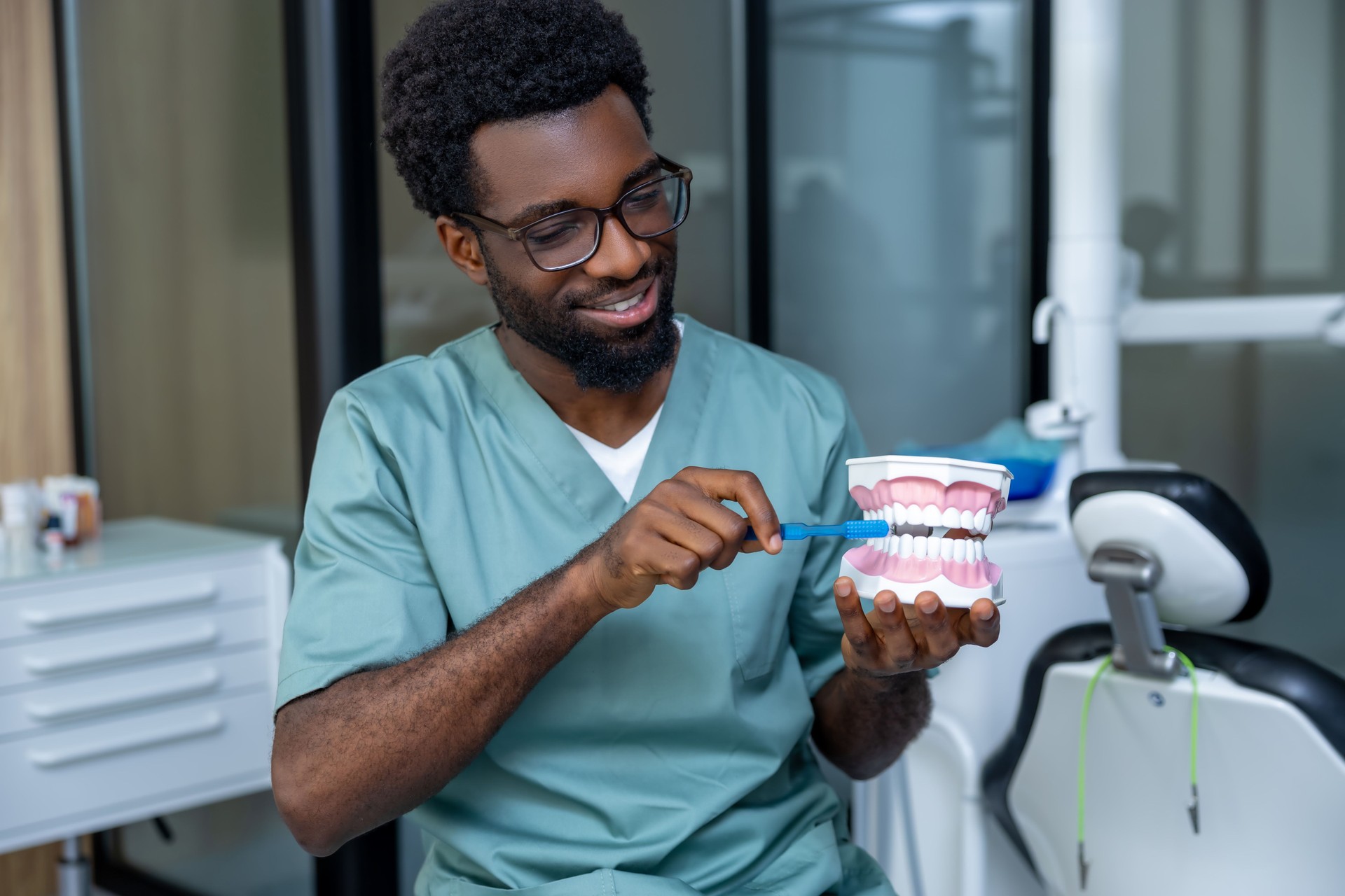 Man dentist wearing uniform holding dentures in office room