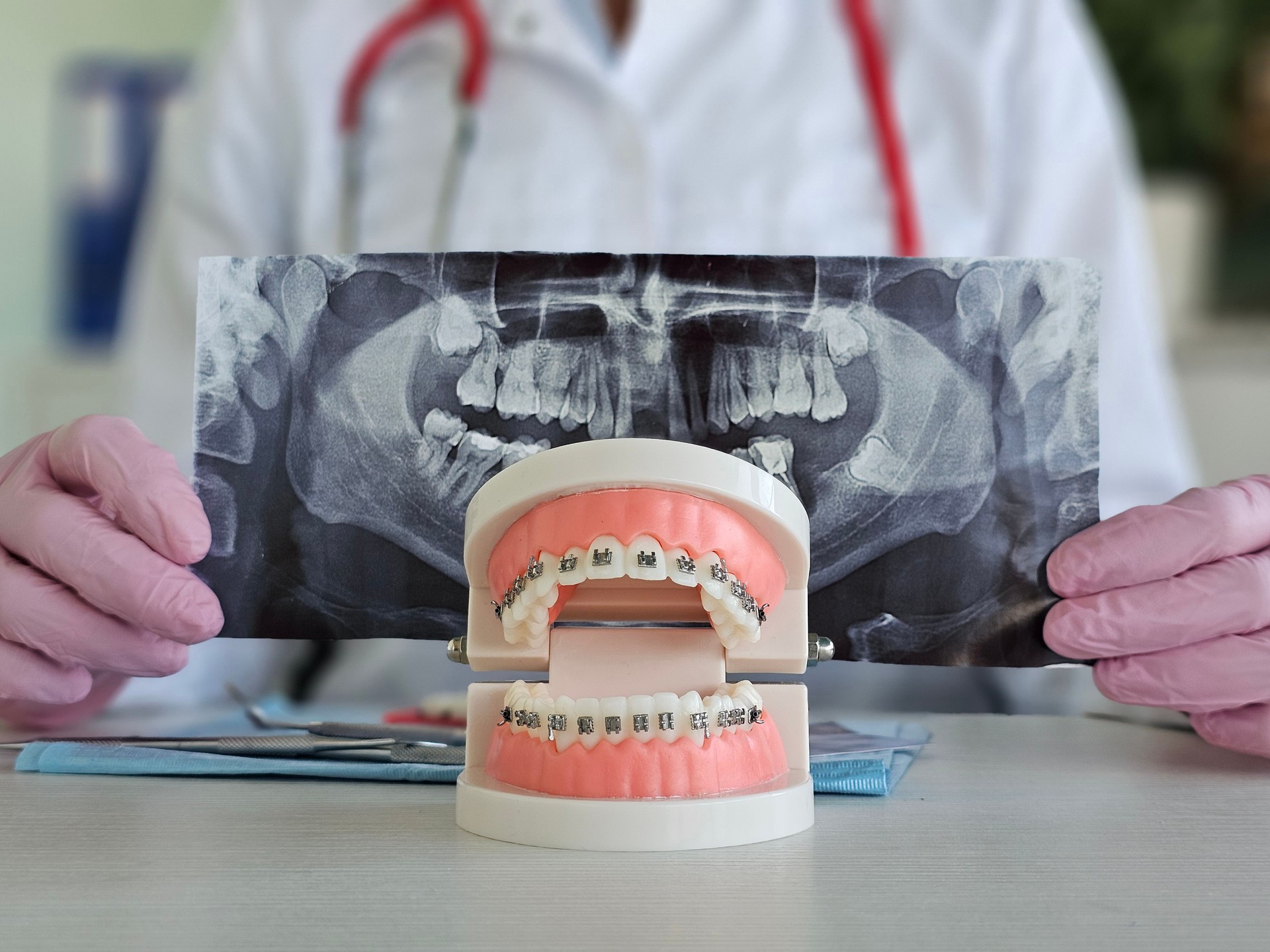 Orthodontist examining orthodontic model alongside dental X-rays in clinical environment concept